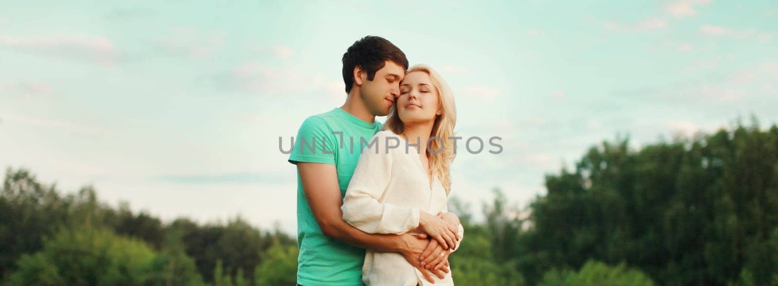 Portrait of beautiful happy smiling young couple in love together hugging in summer park by Rohappy