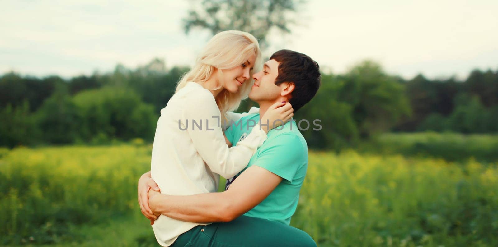 Portrait of beautiful happy smiling young couple in love together hugging in summer park by Rohappy