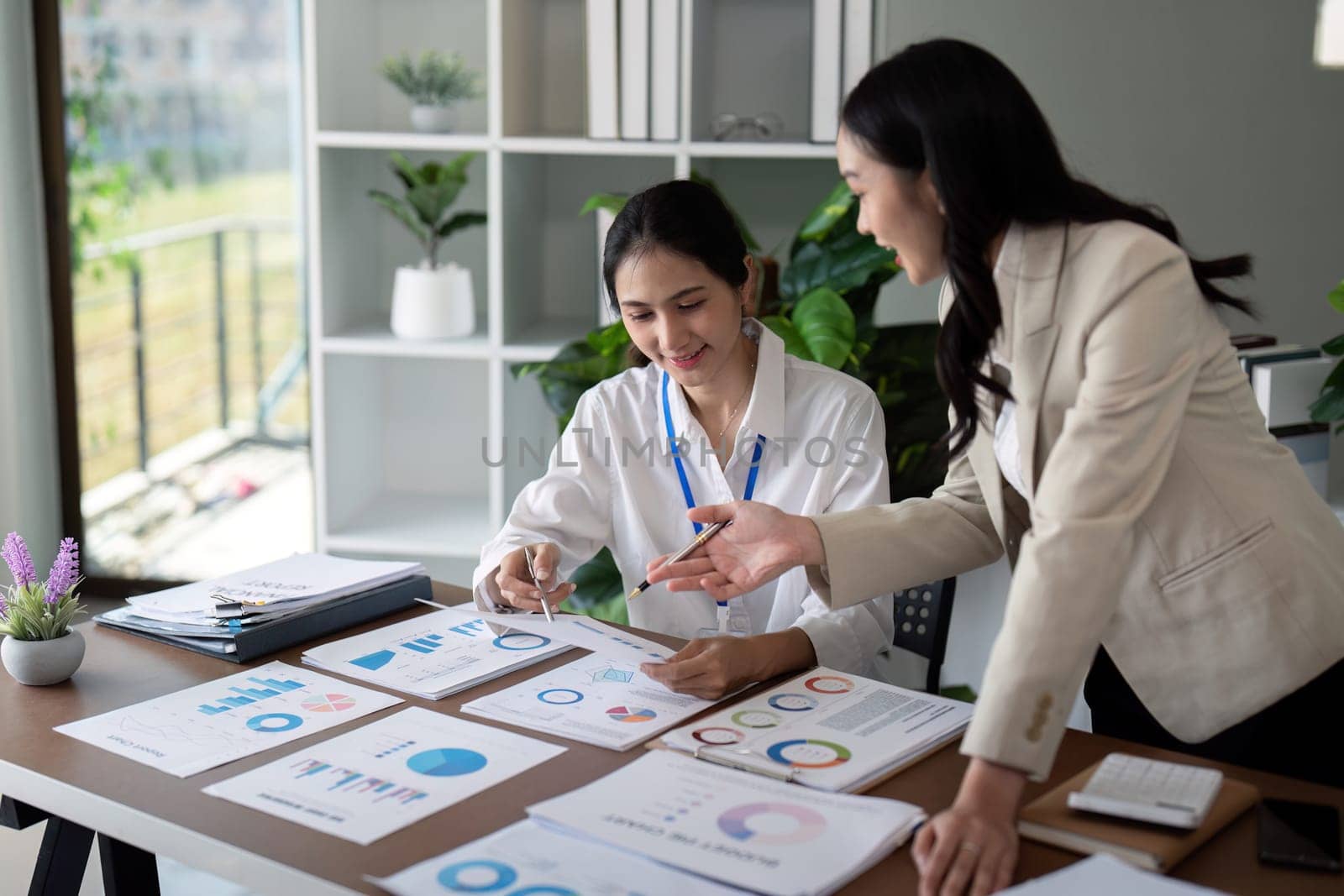 Businesswomen discussing charts and graphs in office. Concept of teamwork and data analysis.