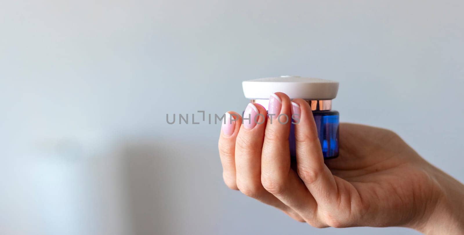 Shot of the beautiful woman's hand holding bottle of skin care product.
