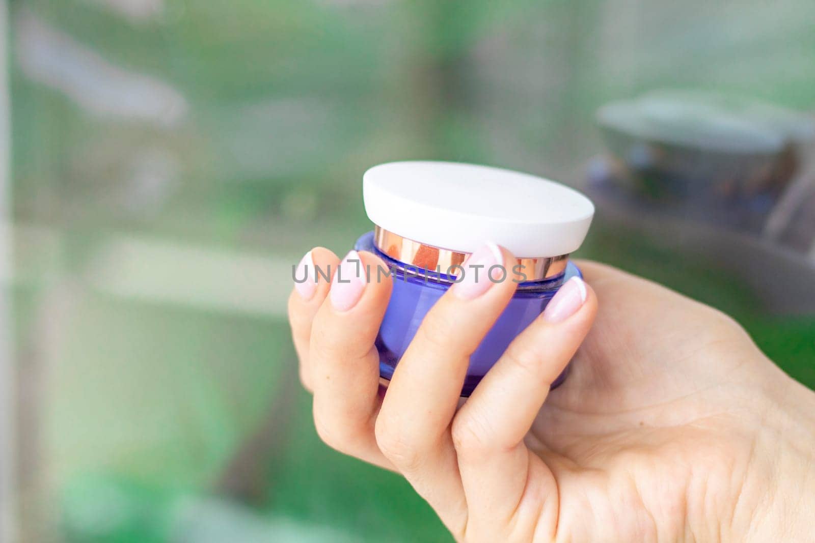 Shot of the beautiful woman's hand holding bottle of skin care product.