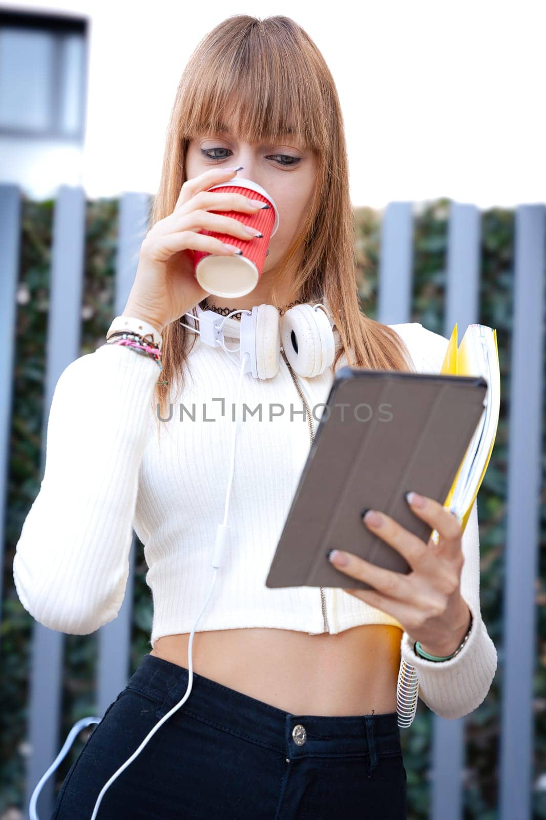 Vertical portrait student surfing the internet with a digital tablet on campus by mariaphoto3