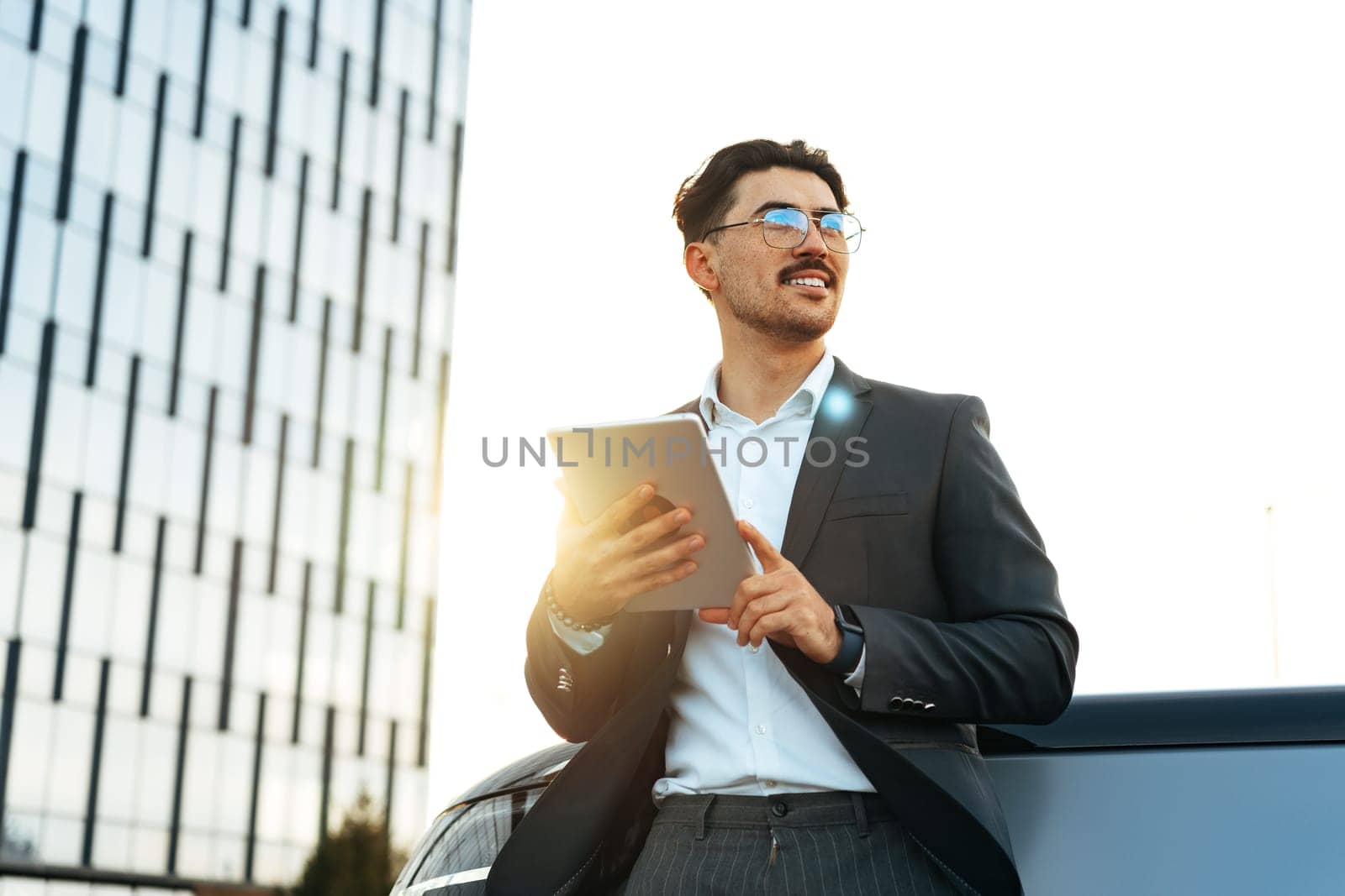 Young businessman using digital tablet while standing outdoors close up