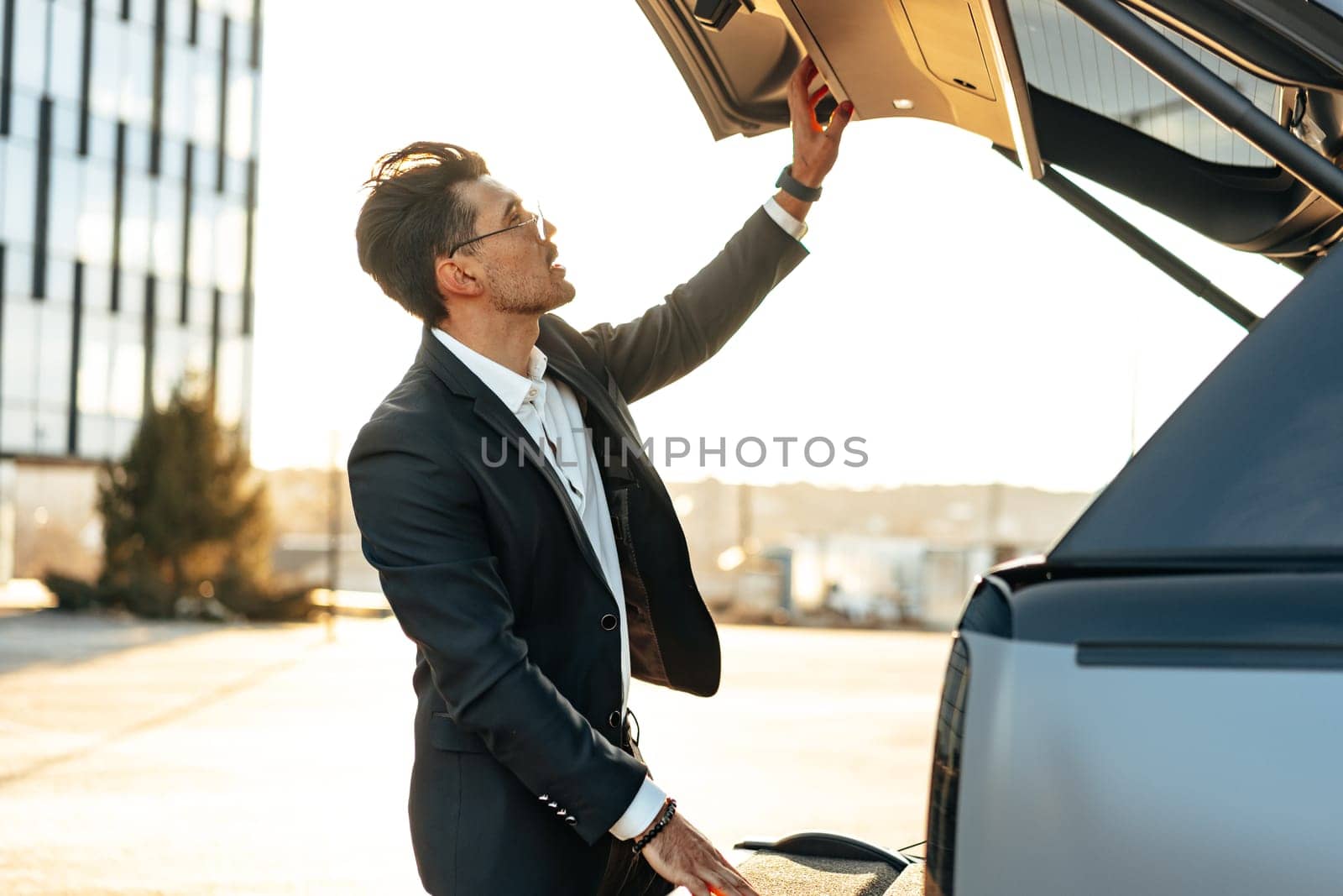 Successful businessman taking luggage from the car trunk outdoors