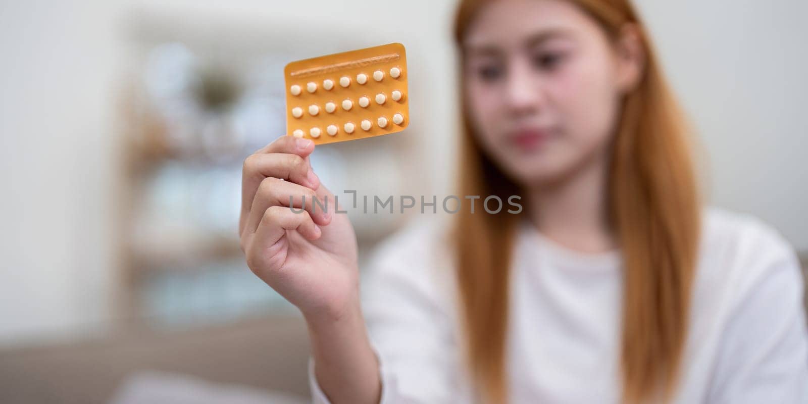 Woman examining a pack of birth control pills. Concept of contraception and reproductive health.