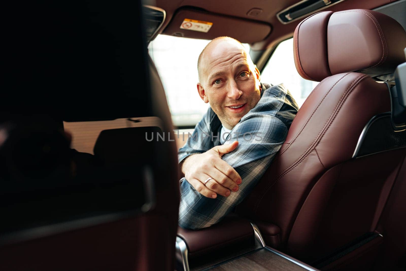 Smiling man in casual clothes sitting in luxury car, portrait