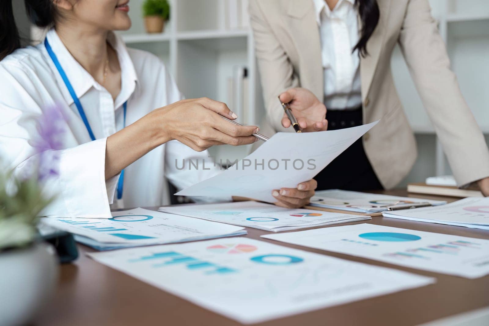 Collaborative business woman meeting hands analyzing financial charts and graphs on office desk for strategic planning.