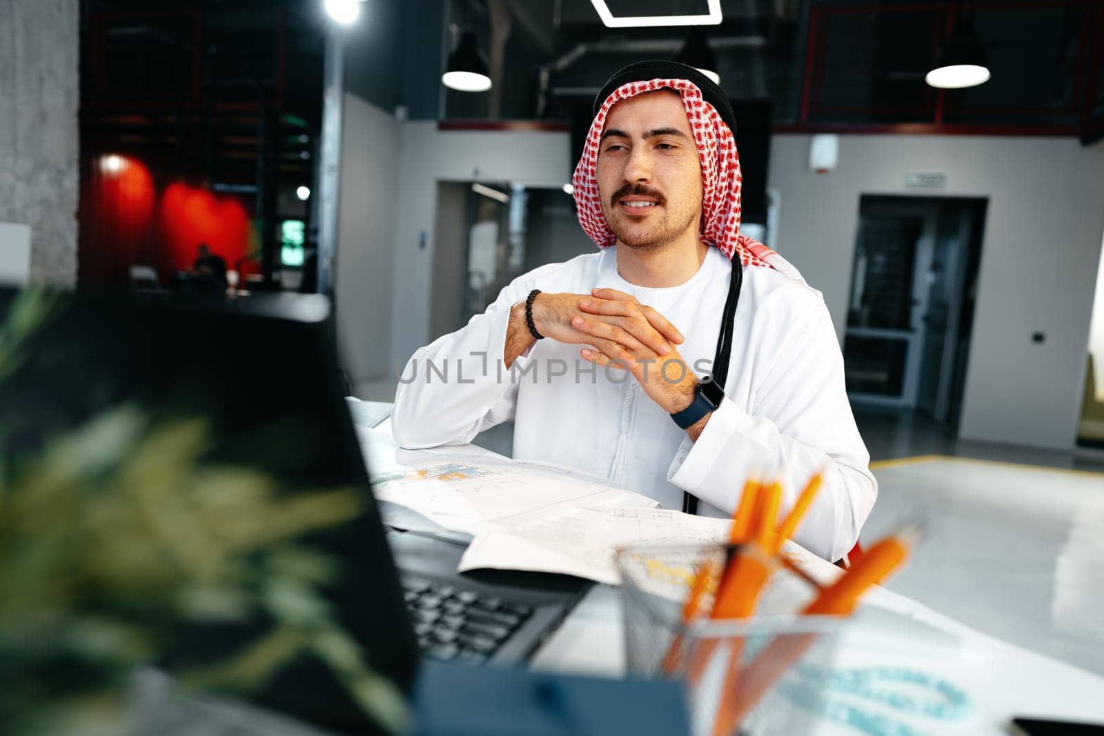 Young muslim businessman in traditional outfit working at the table in office clsoe up