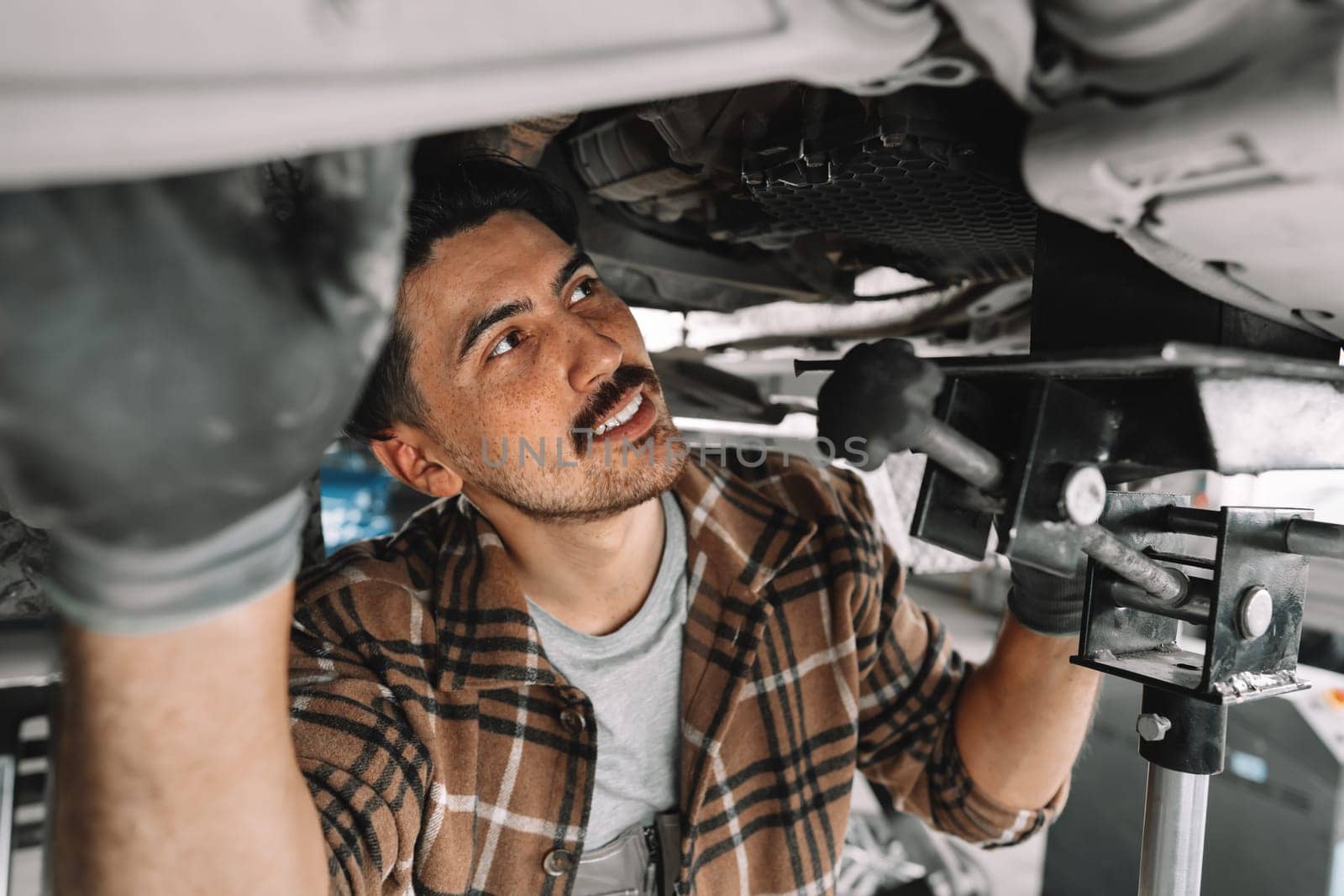 Auto mechanic repairs running gear of a car in car service close up