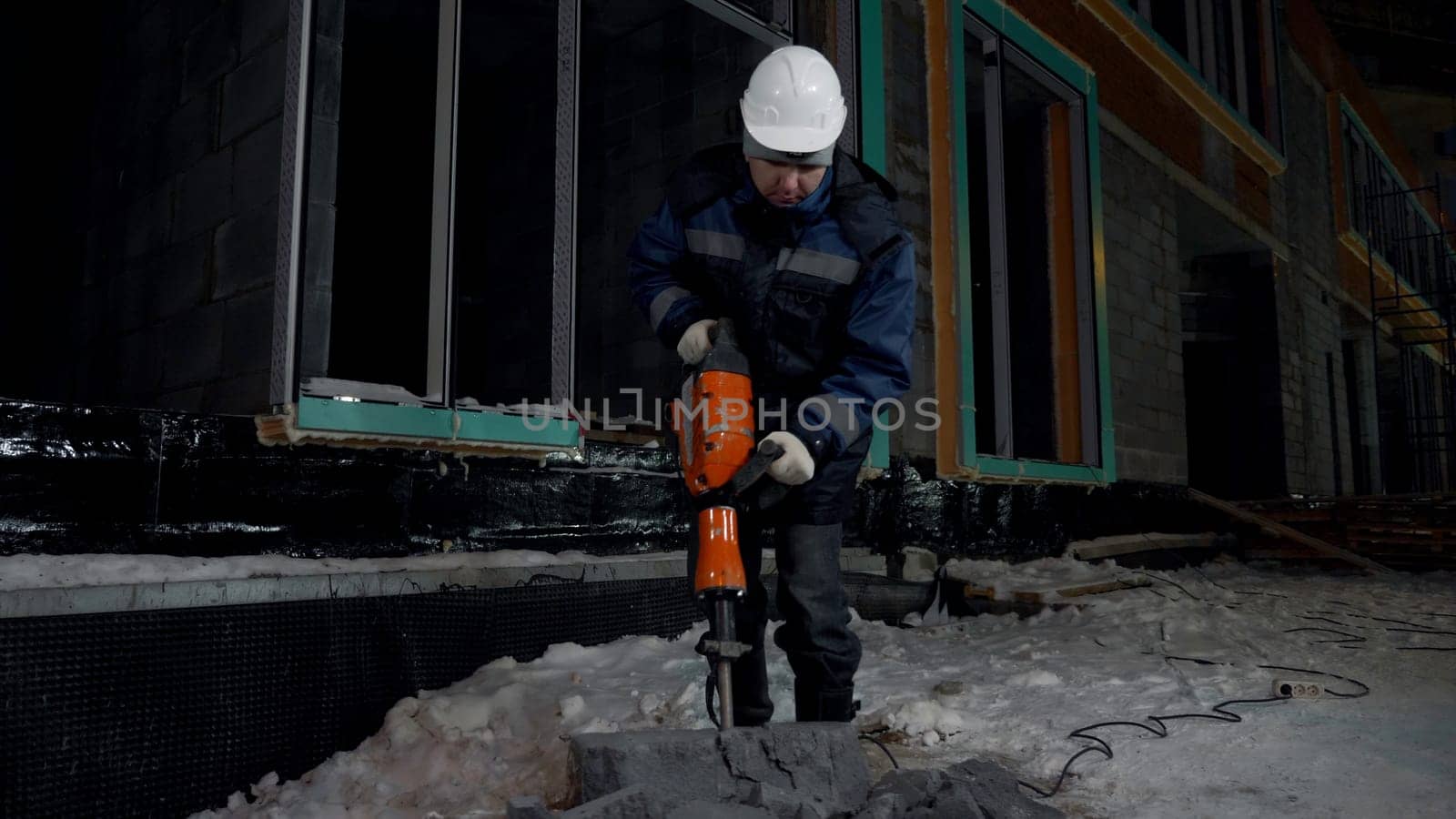 Construction worker uses hydraulic drill at construction site. Clip. Process of crashing a concrete block