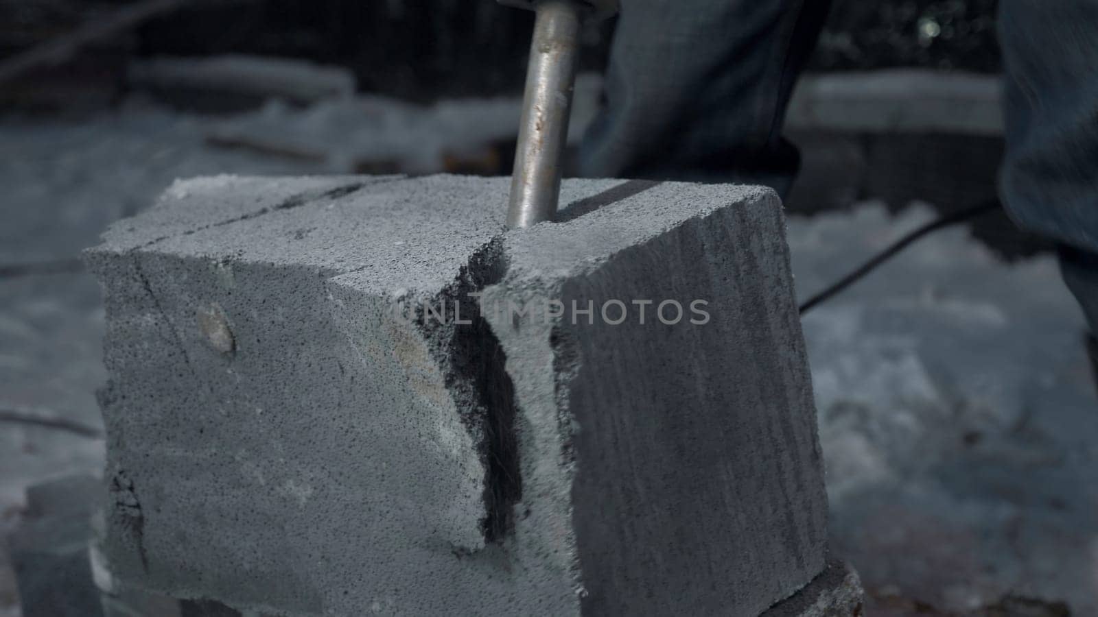 Man drills cement blocks. Clip. Worker splits cement blocks at construction site with hammer drill. Breaking apart cement blocks with drill.