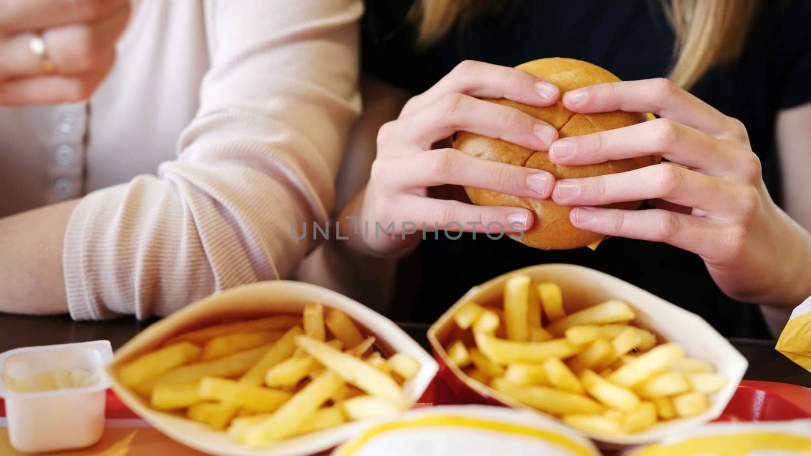 Poznan, Poland - 28 april 2024: Mother And Young Daughter Eating Cheeseburgers At Mcdonald's Fast Food Restaurant