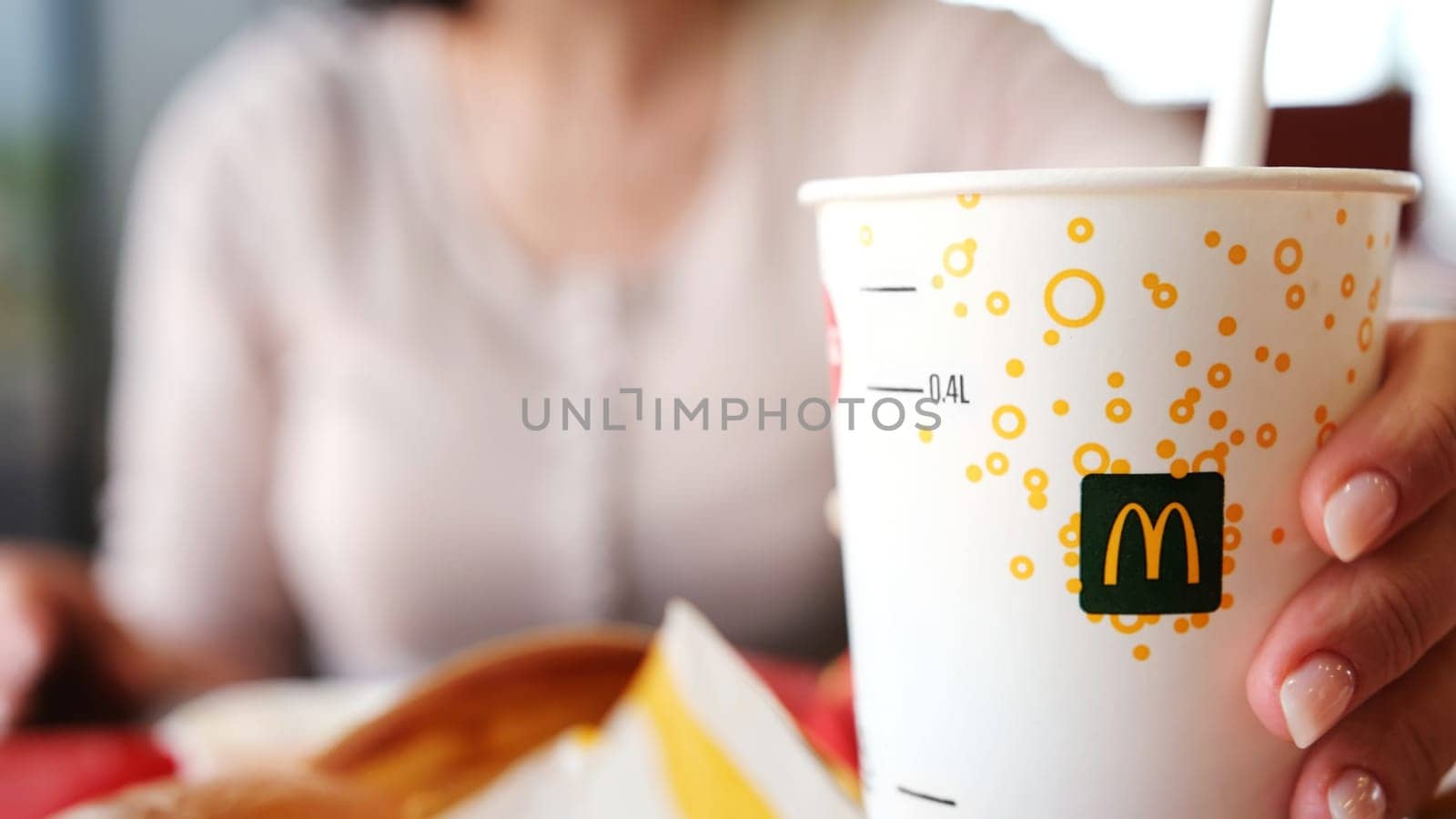 Poznan, Poland - 28 april 2024: Lady Sipping Chilled Soft Drink At Mcdonald's Fast Food Joint