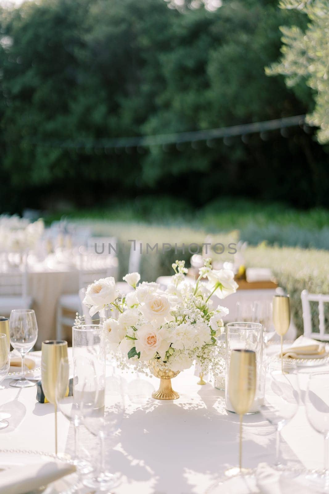 Bouquet of flowers stands on a set table among bronze cups and glasses. High quality photo