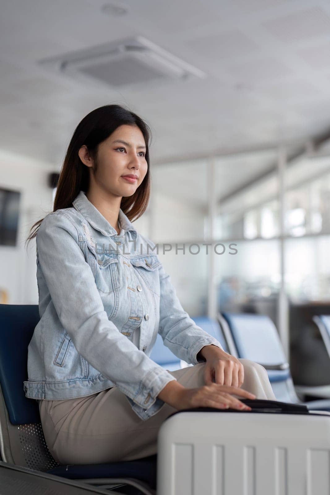 Asian woman waiting at airport terminal. Concept of travel and anticipation.