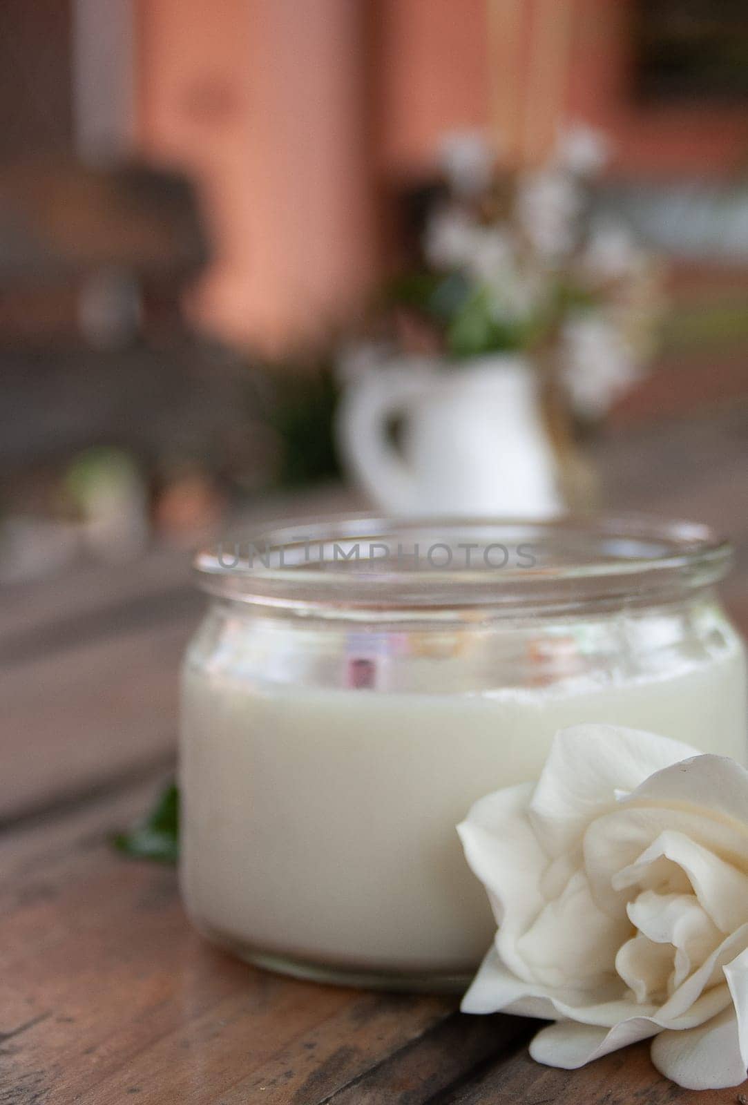 White candle and jasmine on rustic wooden table. Vertical photo