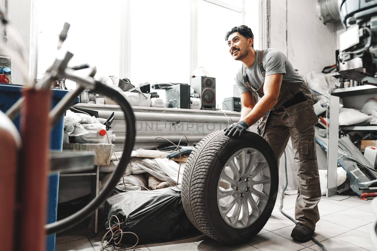 Mechanic pushing a car tire in car service shop