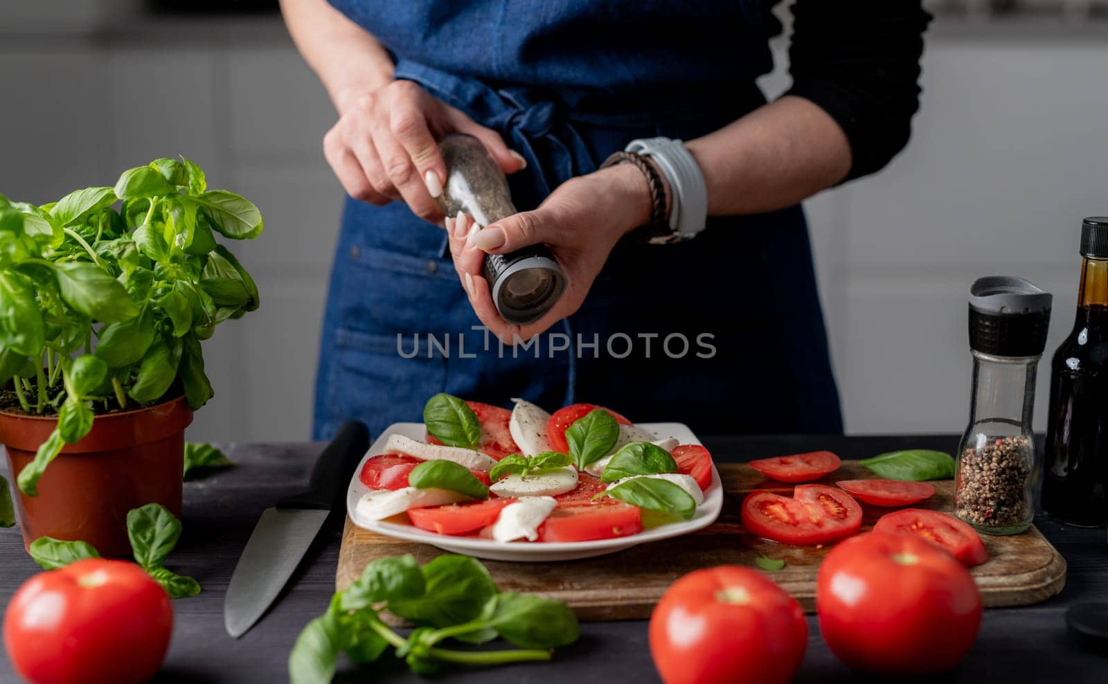 Woman Seasons Caprese Salad Made Of Tomatoes And Mozzarella Cheese