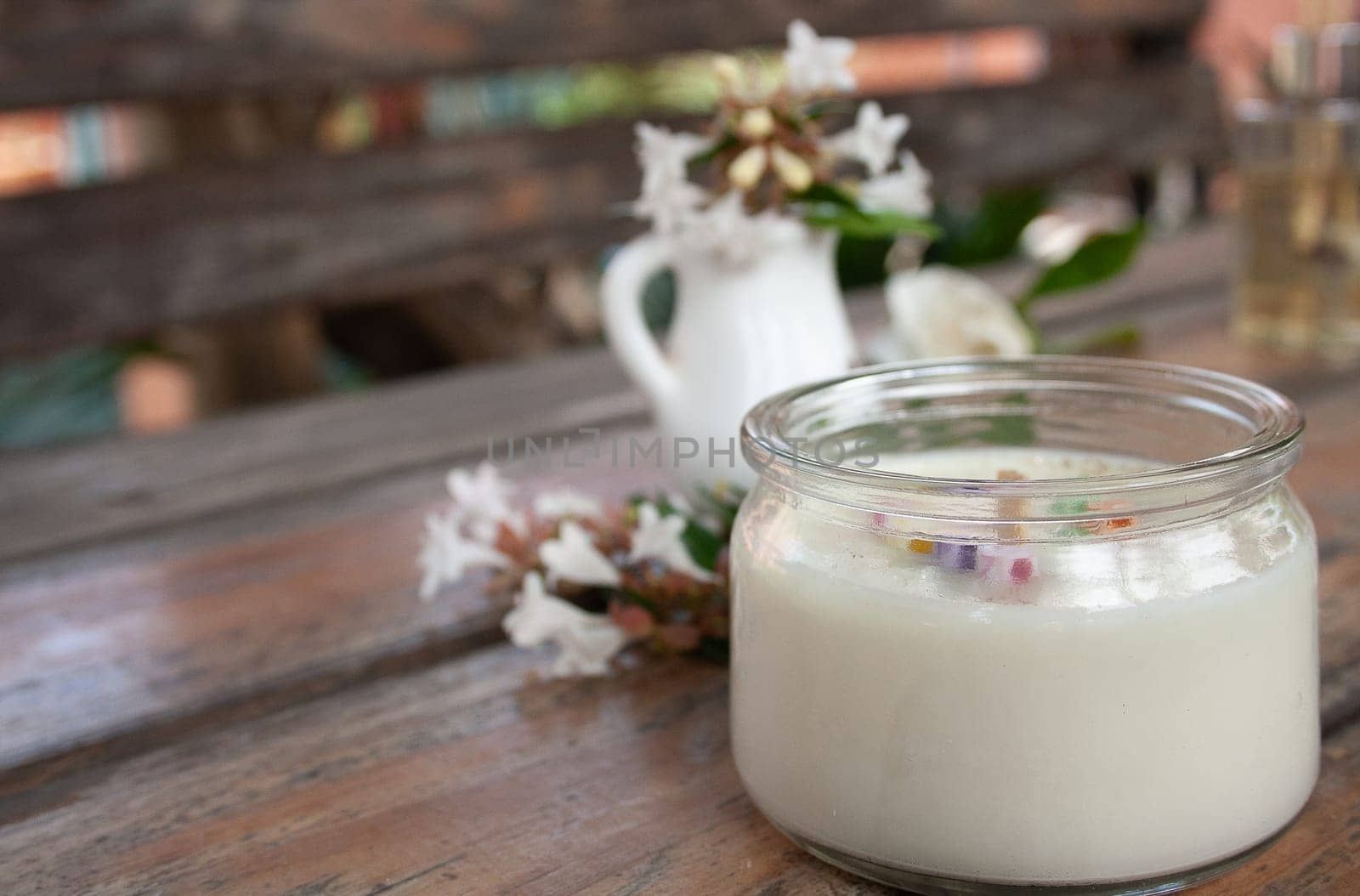 White candle and little jasmine flowers on a rustic wood