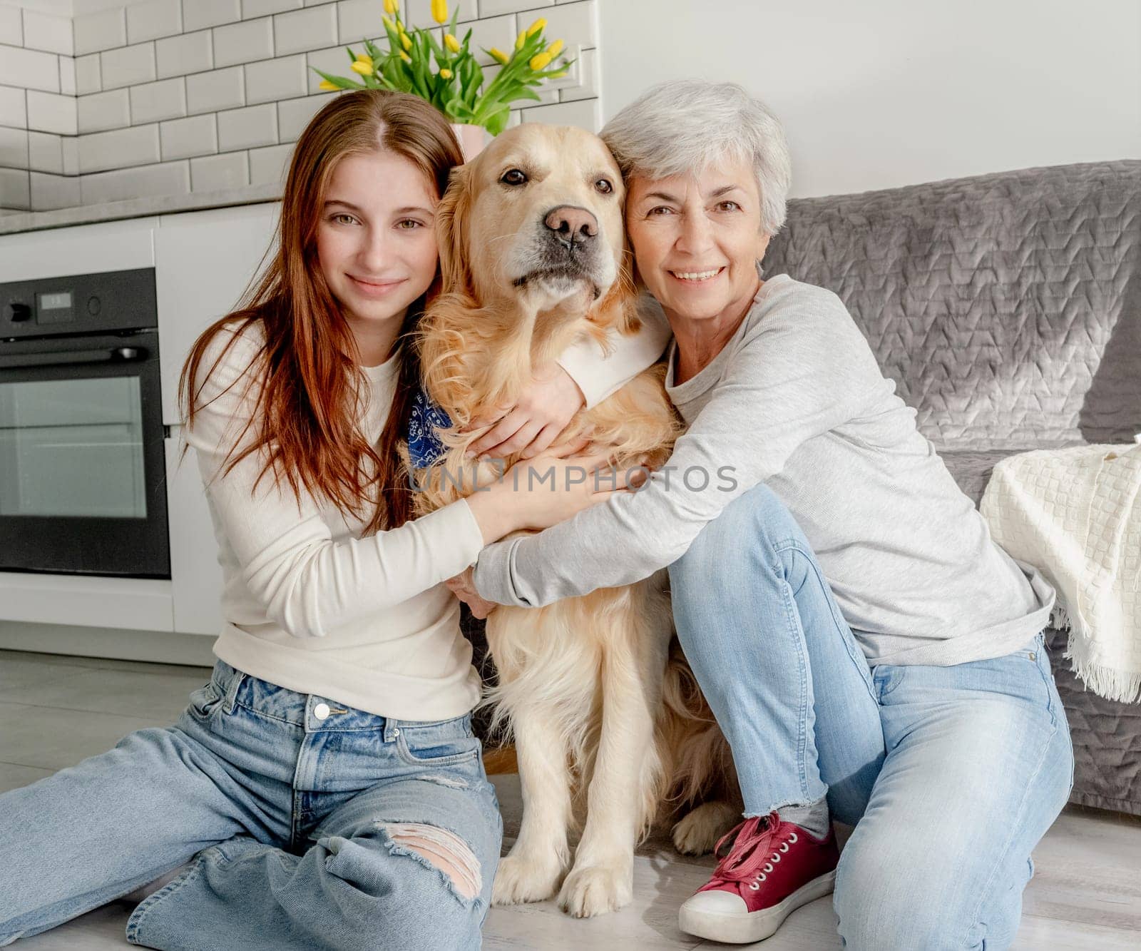 Teenage Girl And Her Grandmother With Golden Retriever Dog At Home In A Portrait