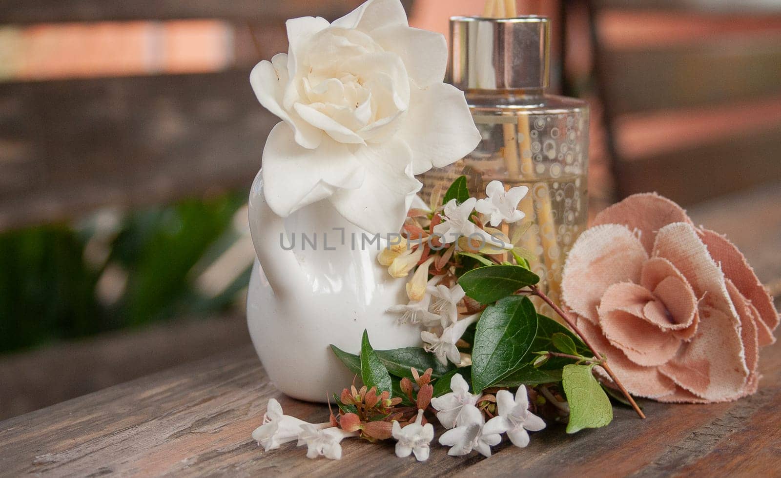 Fragrance diffuser and mixed natural and fabric flowers on rustic table by VeroDibe