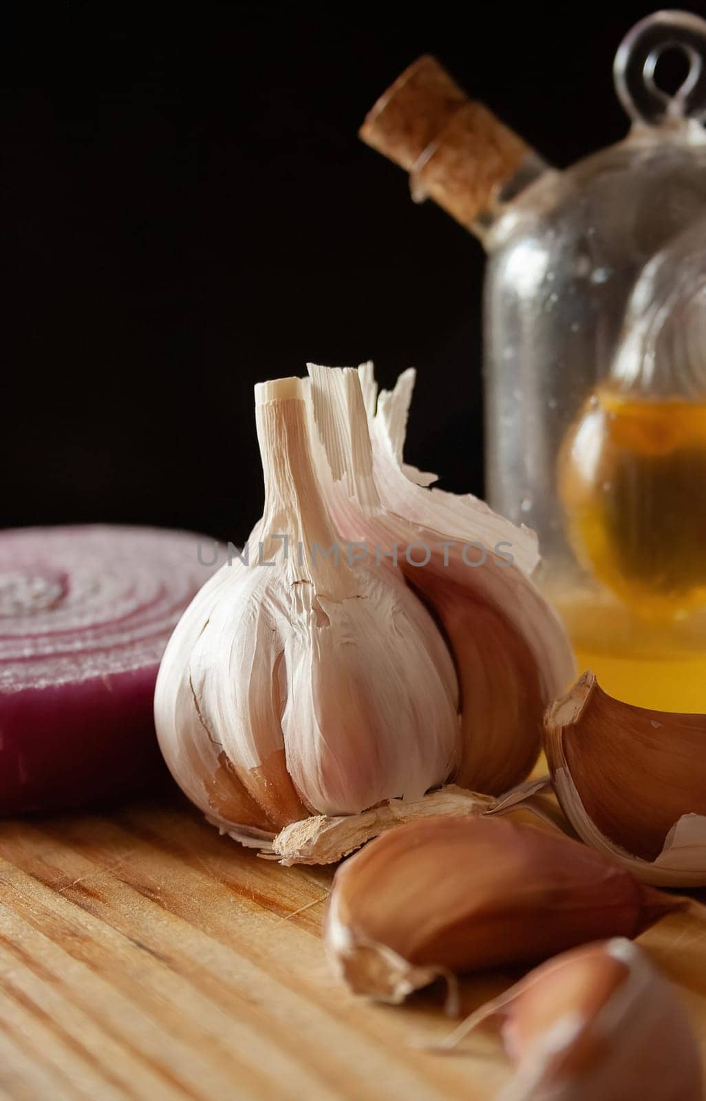 Head and cloves of garlic on a wooden board with black background. Minimalist still life