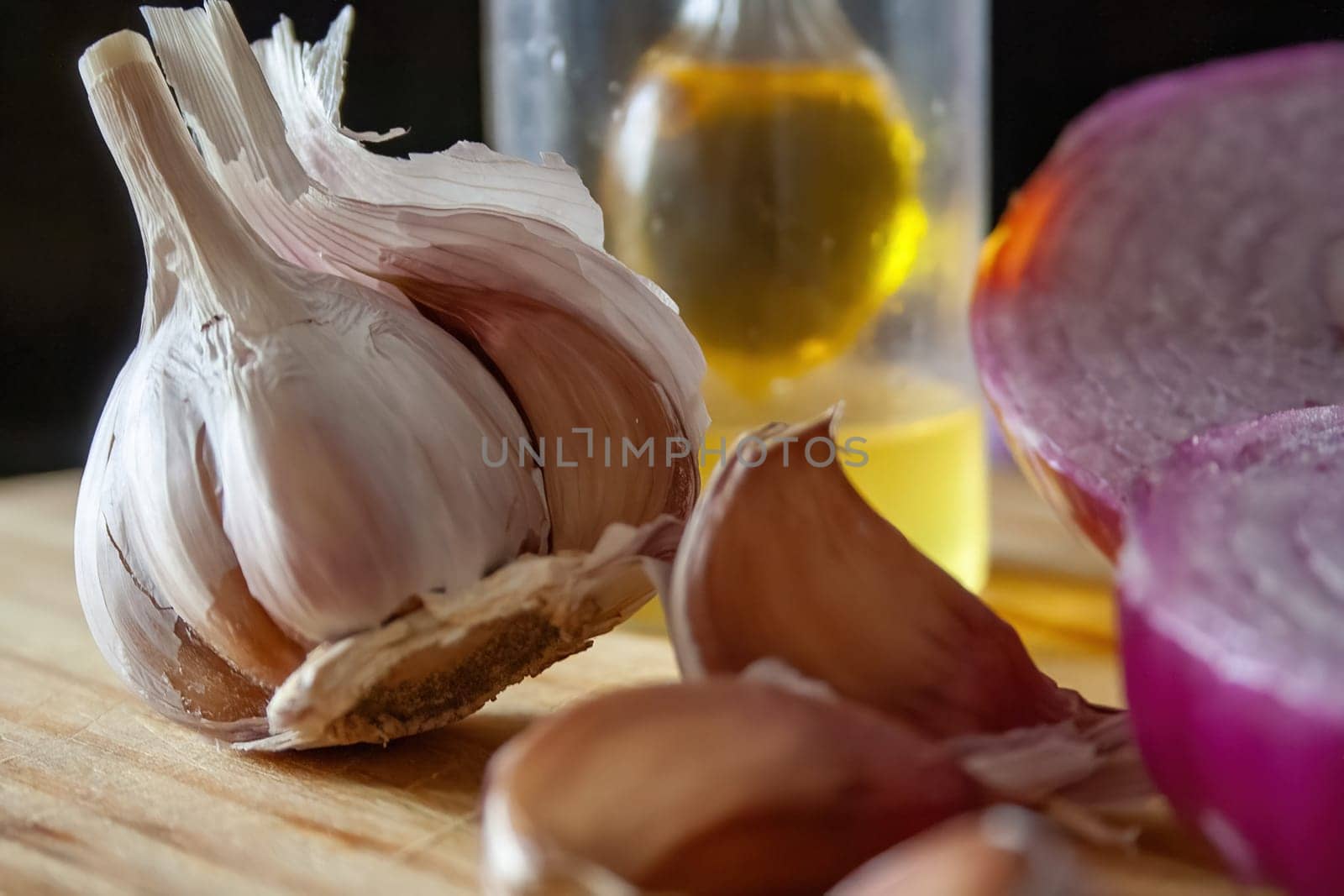 Head and cloves of garlic and olive oil on a wooden board. Minimalist still life