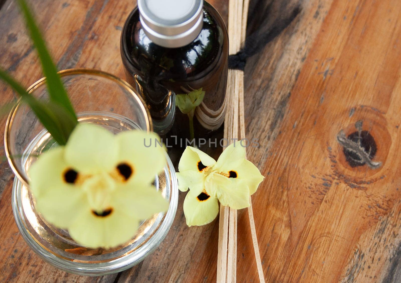 Yellow floral decoration with aroma diffuser on wooden rustic table . Brown background