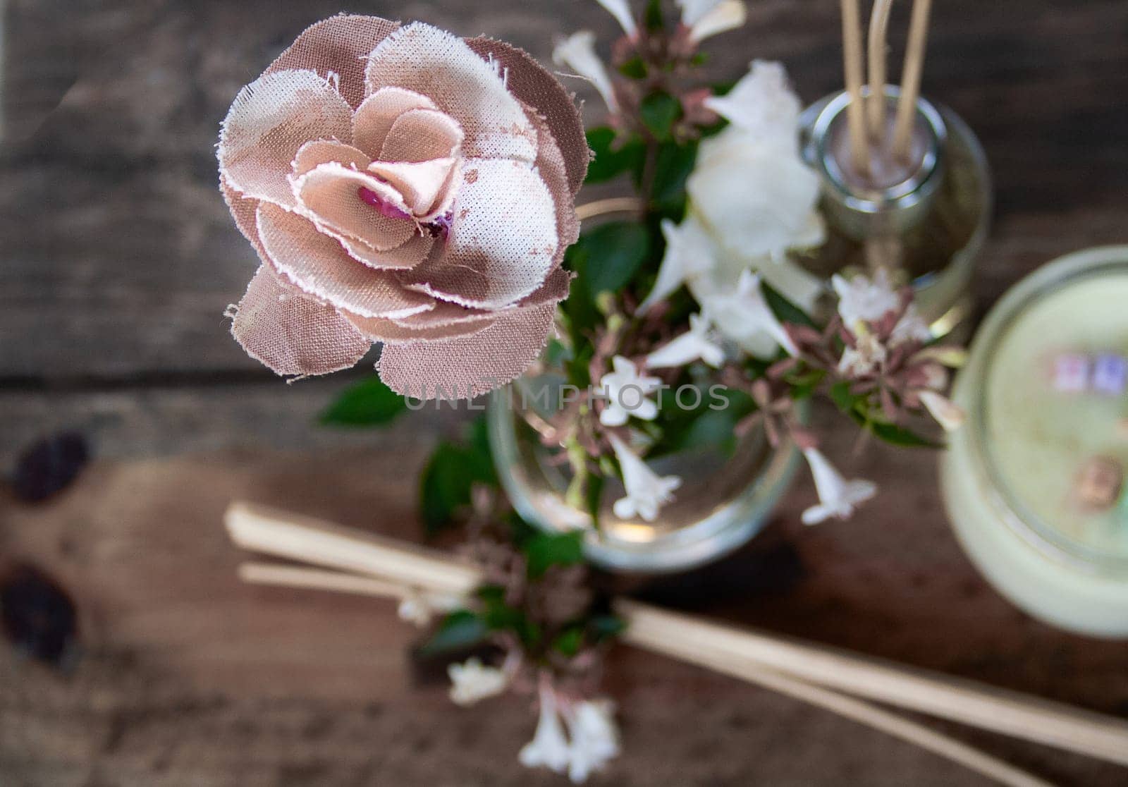 Spa set with scented candle and flowers in wooden background.