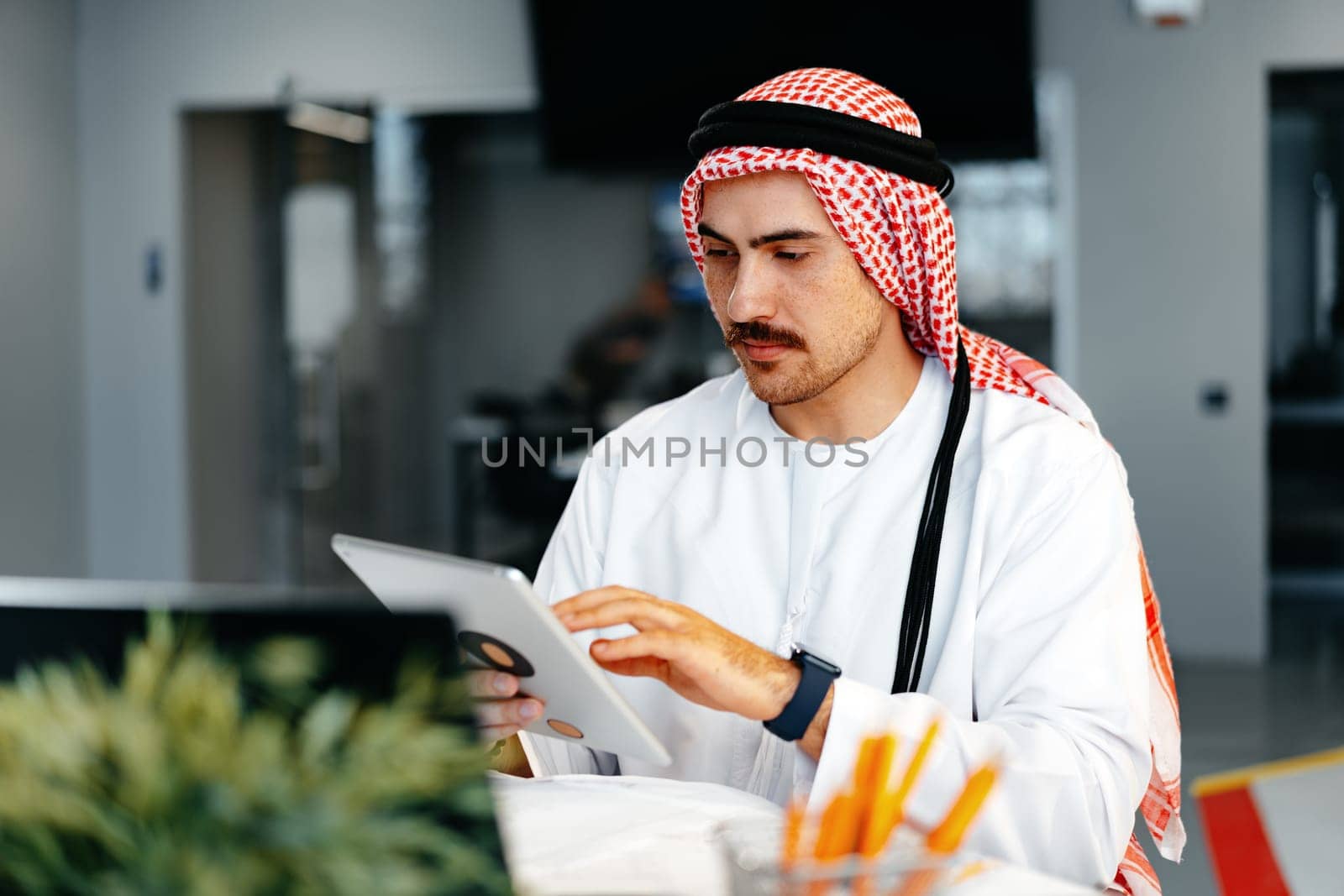 Arab muslim businessman using digital tablet in modern office close up