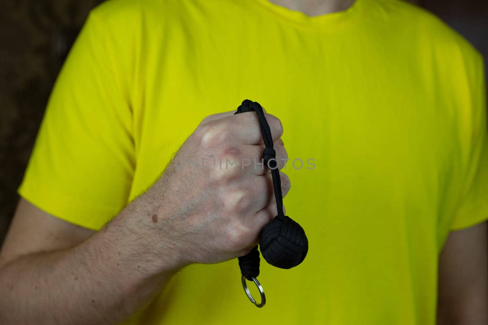 Self-defense keychain made of braided laces with monkey knot with metal ball, baton for self-defense against a criminal on man hand