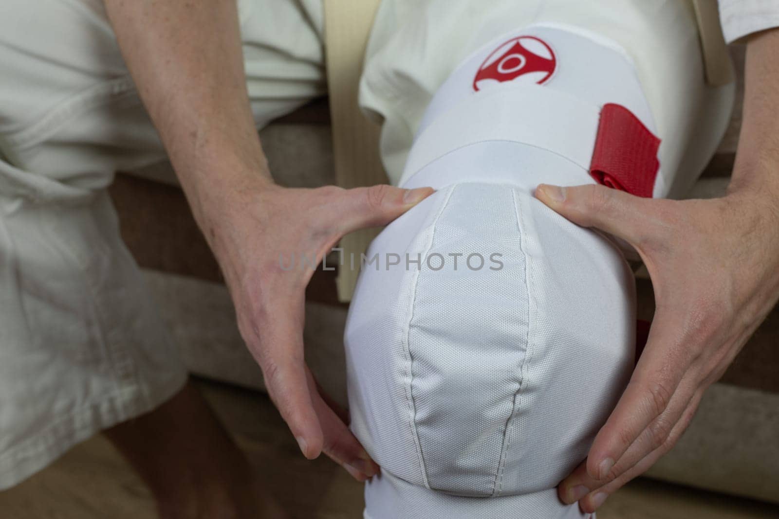 Kyokushinkai karate athlete adjusts protective equipment on his leg, martial arts knee protection, leg guards