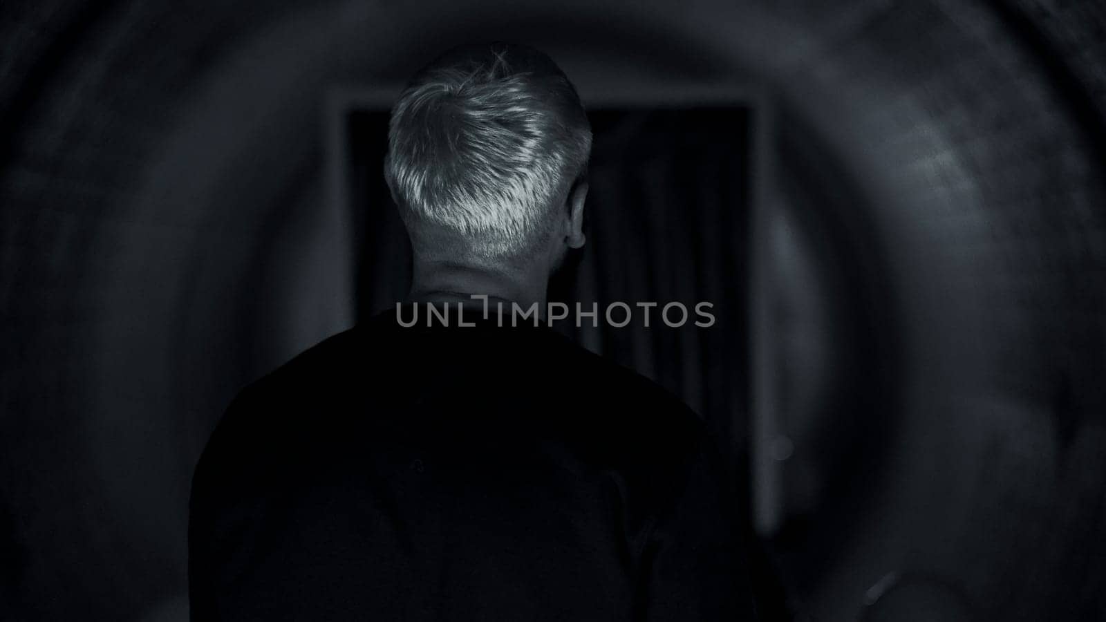 Rear view of a young rapper performer feeling anxiety before going on stage. Media. Man in a corridor with the effect of spinning walls