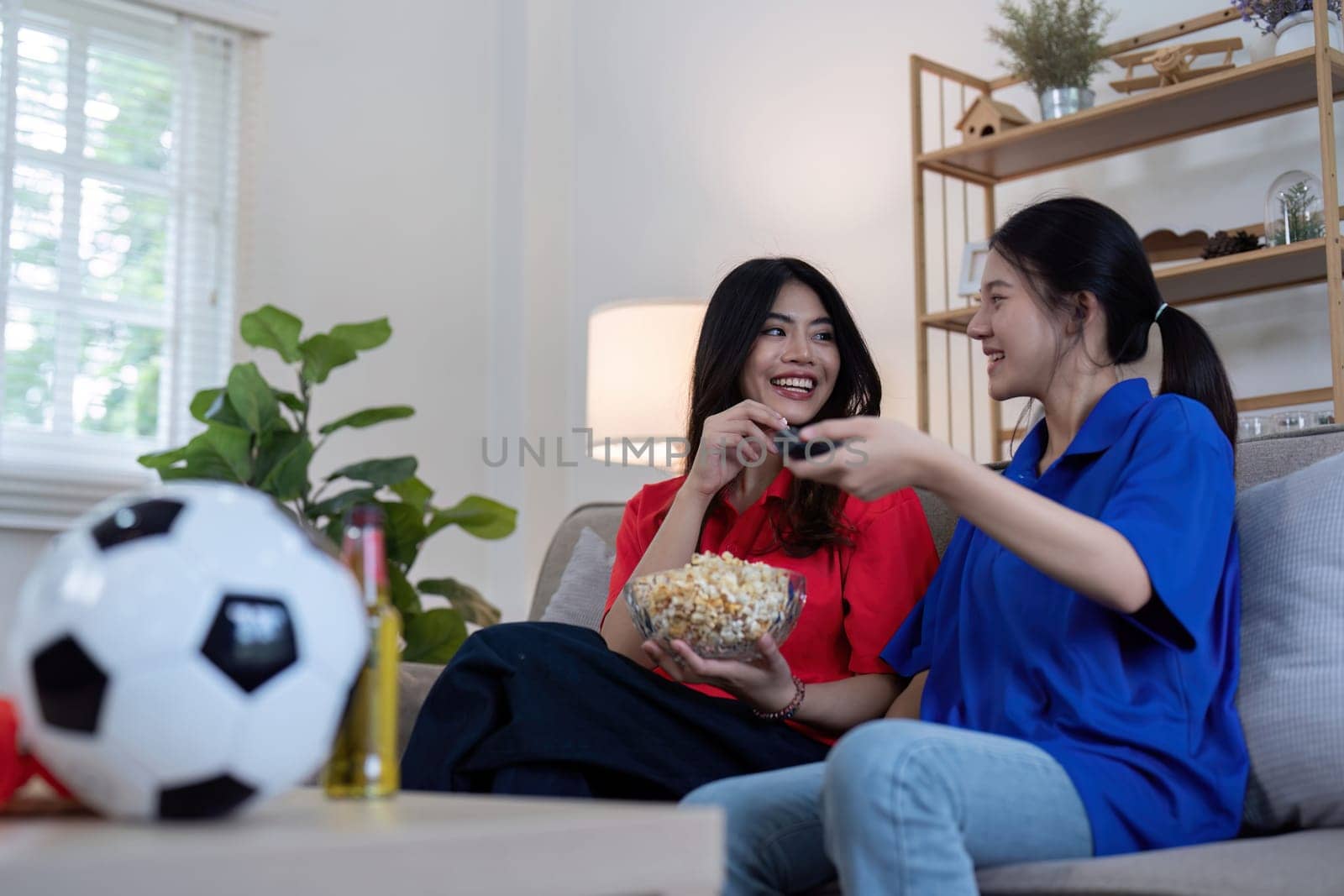 Asian lesbian couple watching Euro football match at home. Concept of cheer and football.