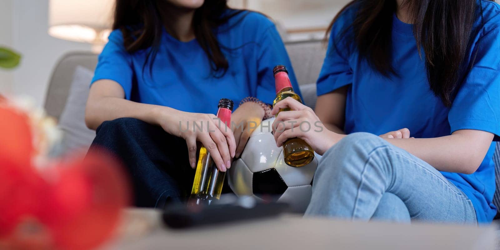 Lesbian couple cheering for Euro football match at home. Concept of excitement and unity.