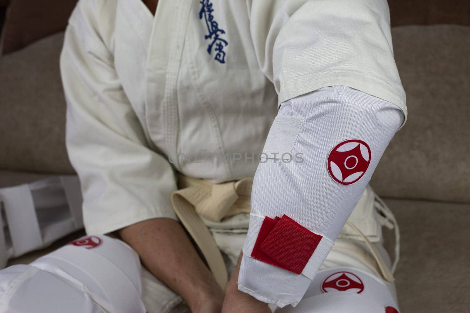 Kyokushinkai karate athlete wears elbow protection, protective equipment for martial arts sparring, health protection in karate