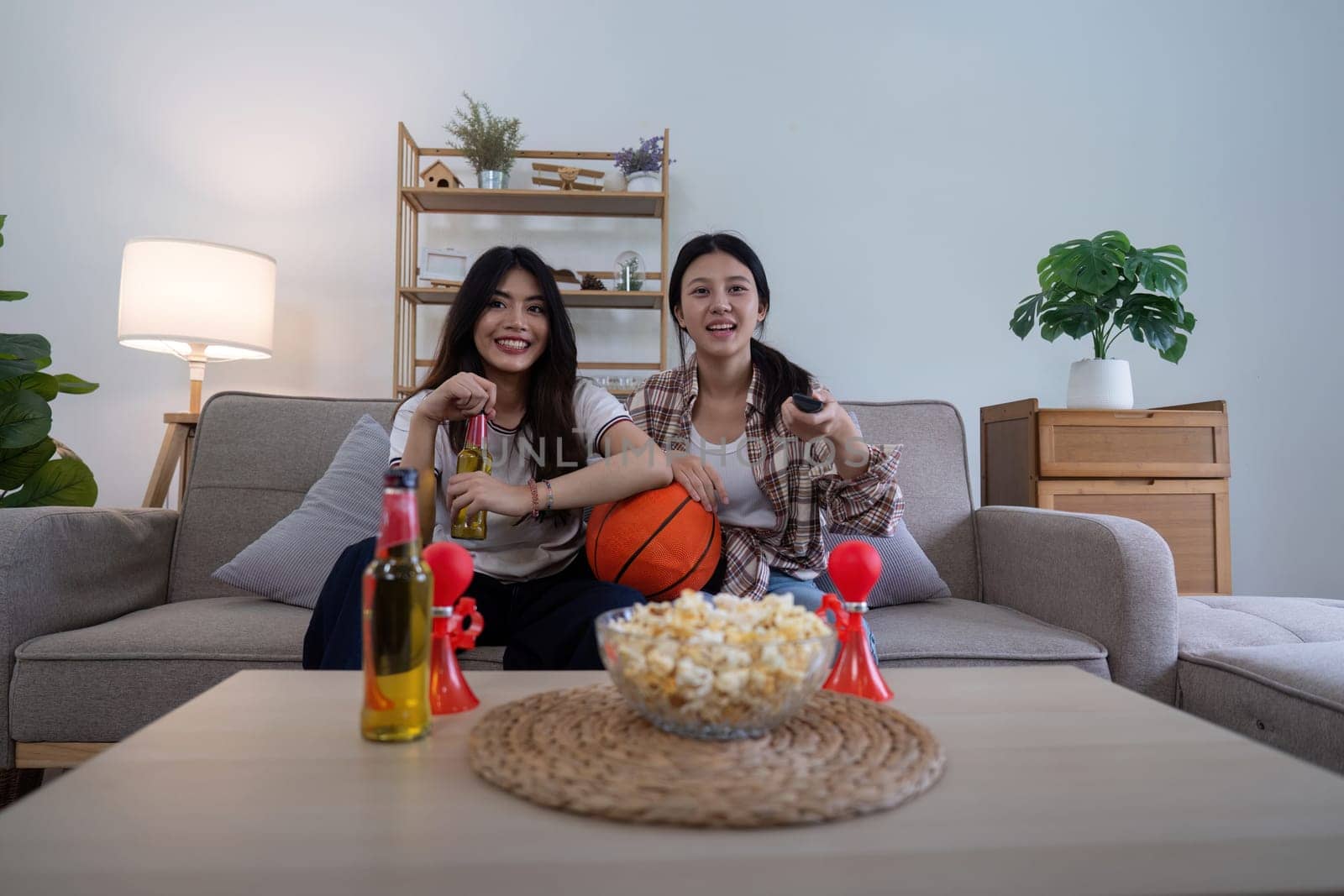 Asian friends cheering while watching basketball at home. Concept of sports and friendship.