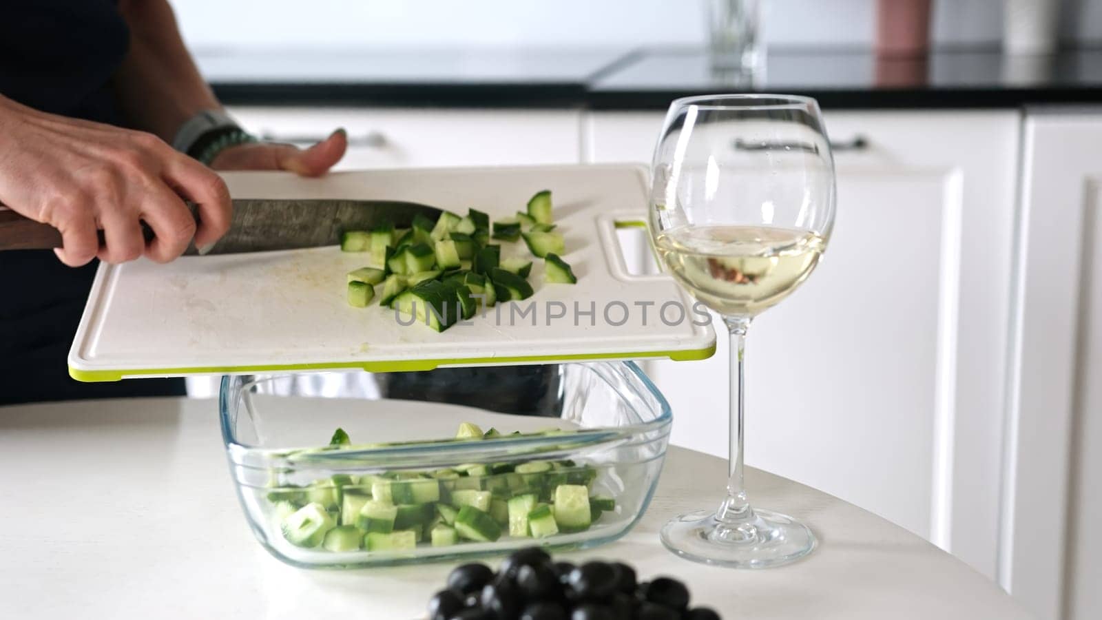 Girl Pours Chopped Cucumbers Into Bowl For Greek Salad by tan4ikk1