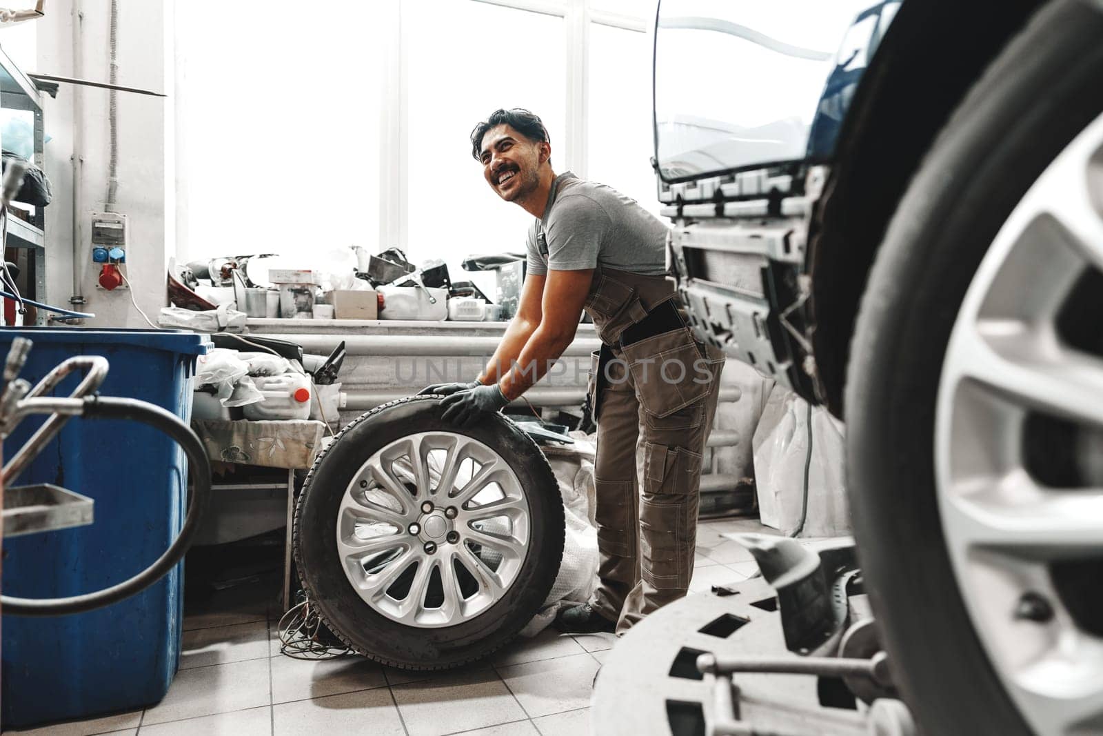 Mechanic pushing a car tire in car service shop