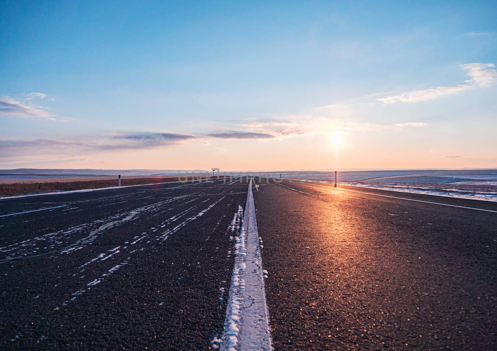 Empty rural road at sunsetin winter with clearing skies