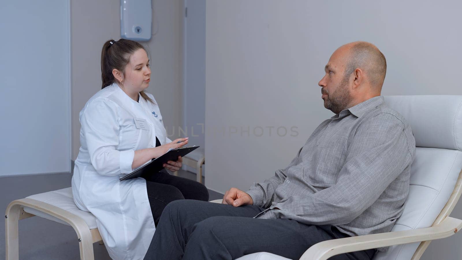 Doctor working in the office and giving recommendations to the patient. Clip. Young female doctor explaining symptoms to male patient, health care and assistance concept. by Mediawhalestock