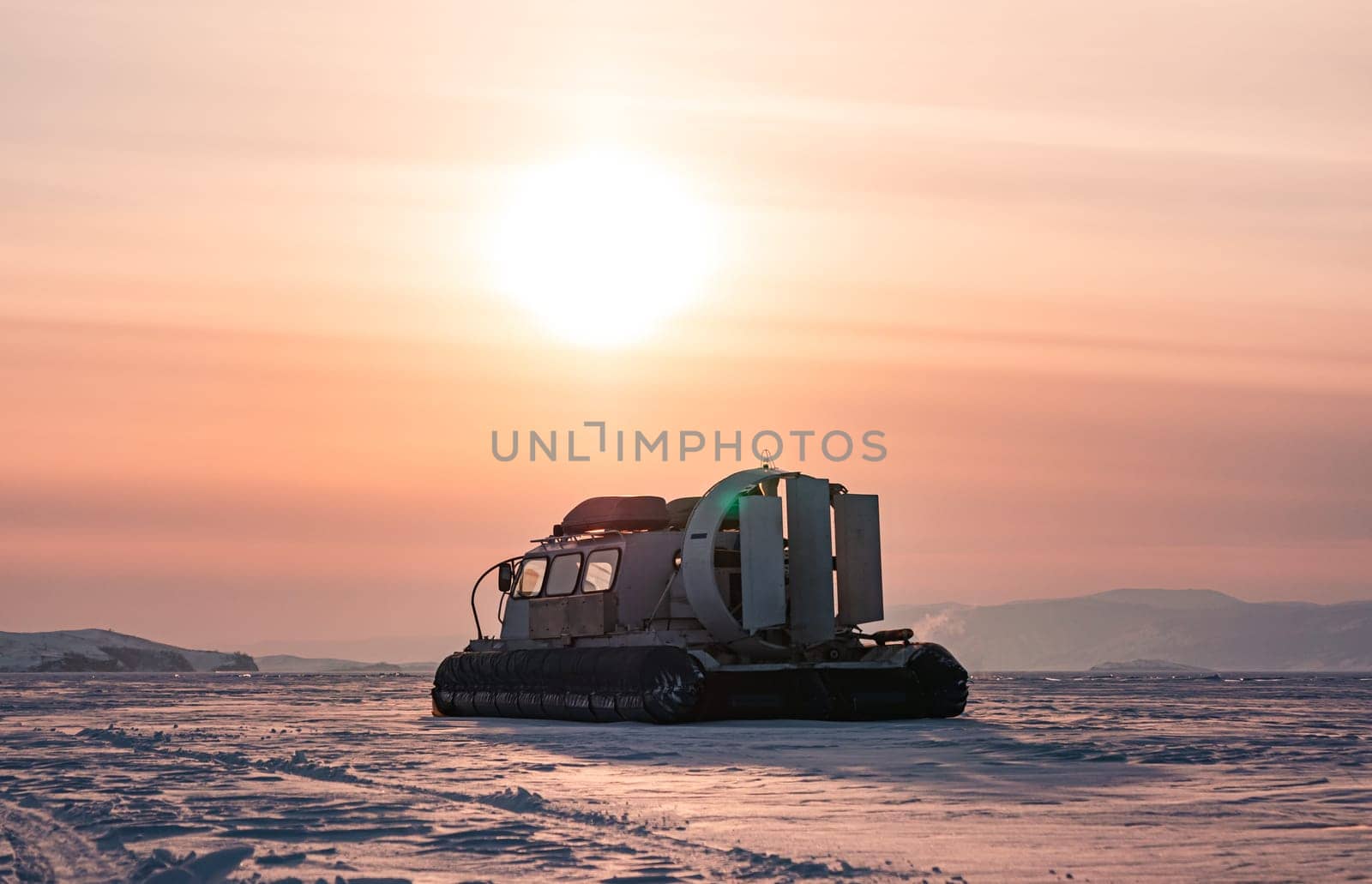 Hovercraft standing on snow covered ice surface of Lake Baikal at dusk.