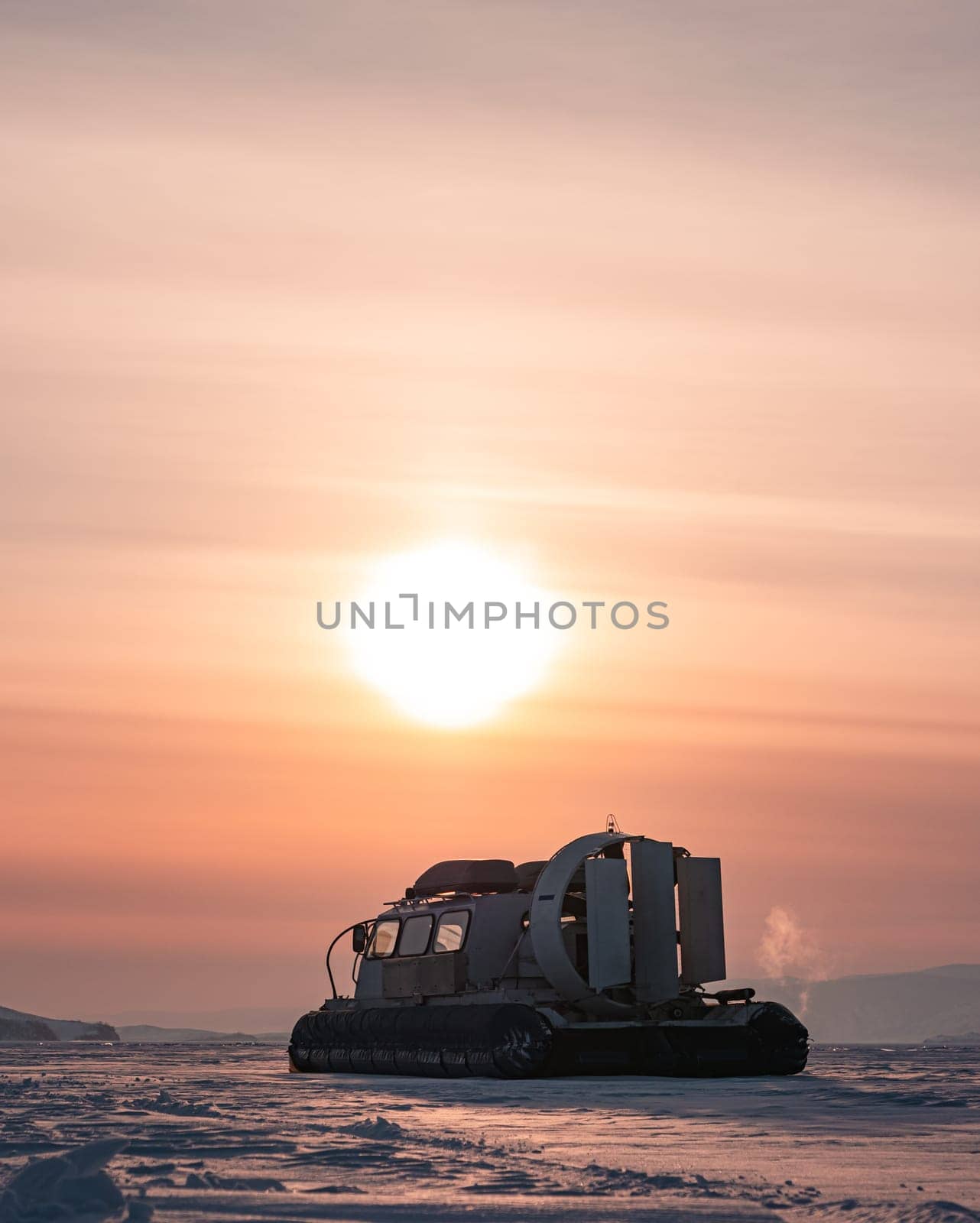Hovercraft standing on snow covered ice surface of Lake Baikal at dusk.