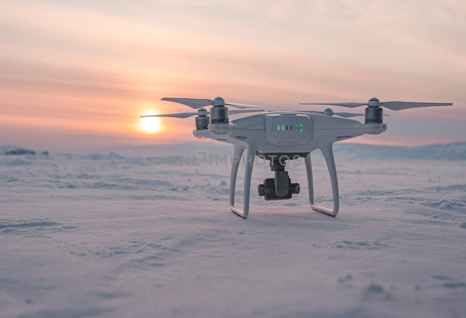 Khuzhir, Russia - March 01, 2021: DJI Phantom 4 PRO drone on snow-covered lake baikal at sunset during winter. by Busker