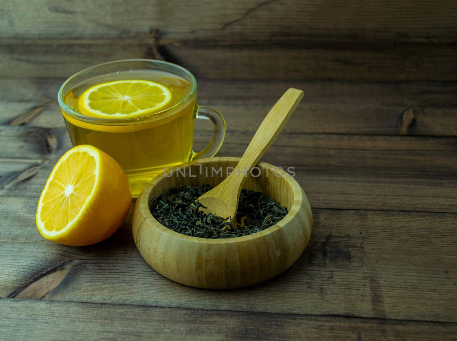 Green tea in a mug, lemon and dry tea. Green tea in a glass mug, lemon and dry tea in a cup on a wooden table.