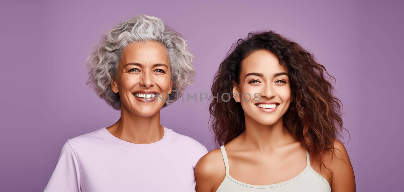 Portrait of happy smiling mature mother and adult daughter, two women together looking at camera on color studio background