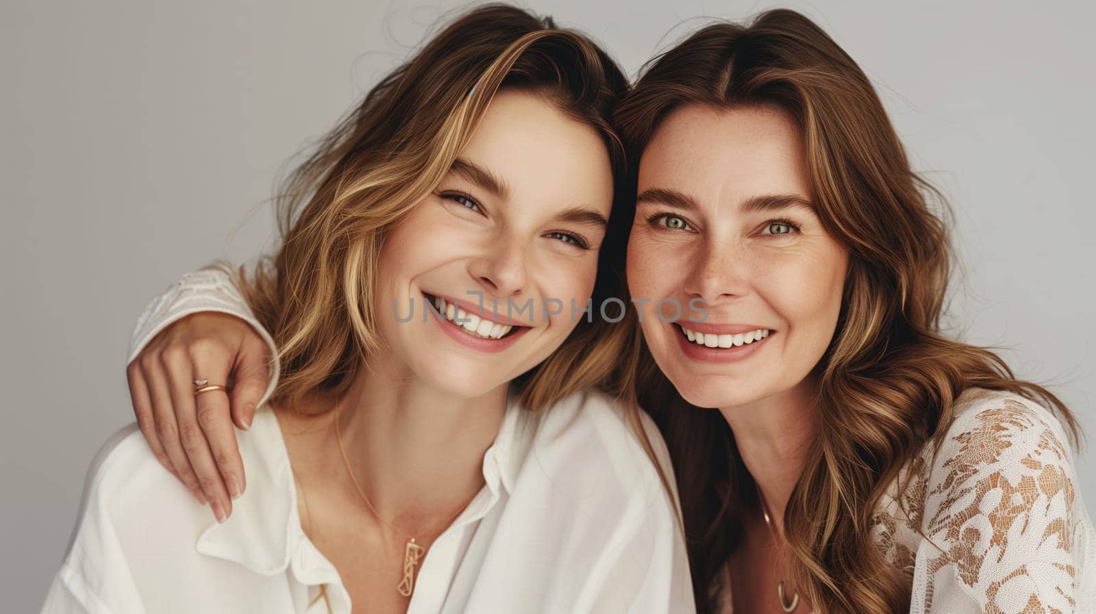 Portrait of happy smiling mature mother and adult daughter, two women together looking at camera on studio background