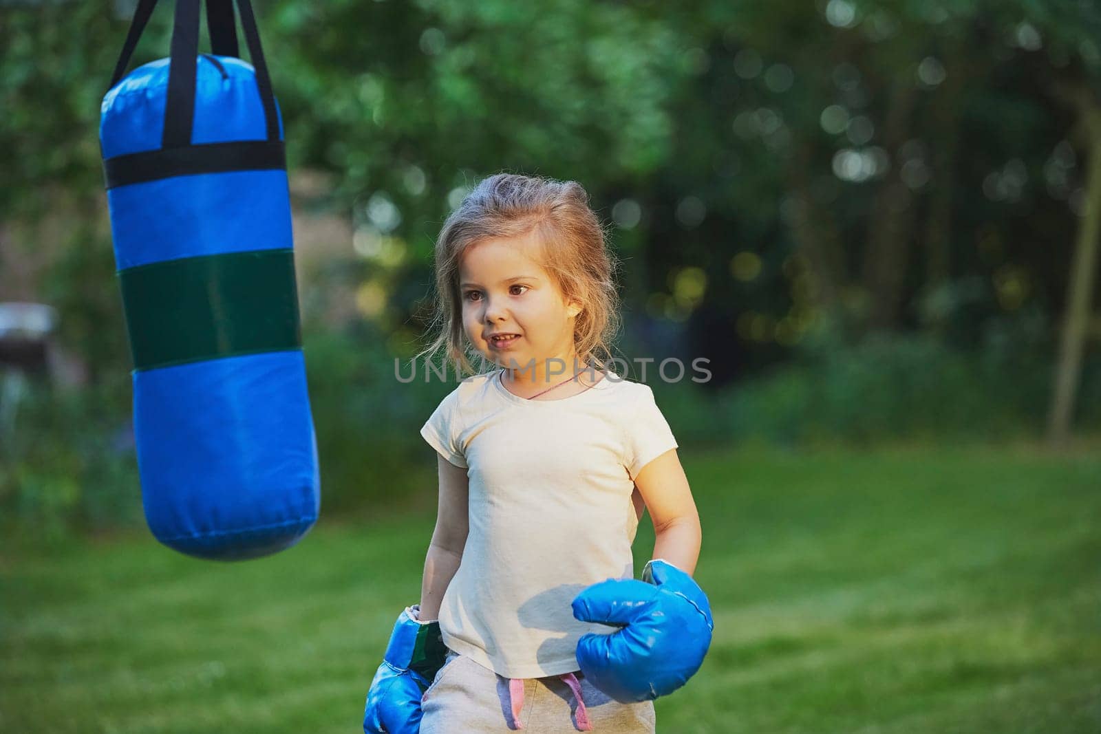Charming child doing boxing in the backyard on the Sunset.