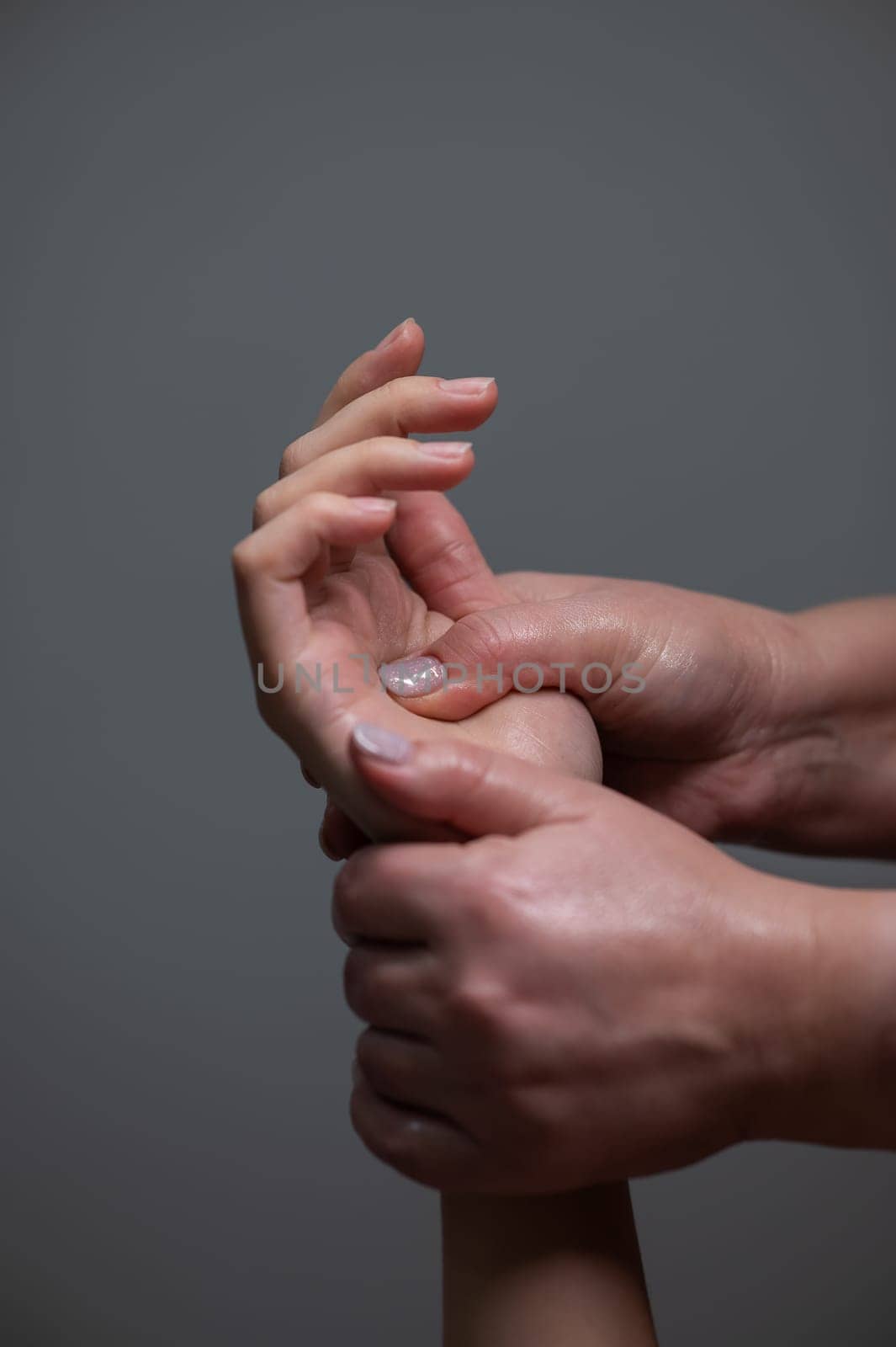 The masseuse massages the client's palms. Close-up of hands at a spa treatment. Vertical photo