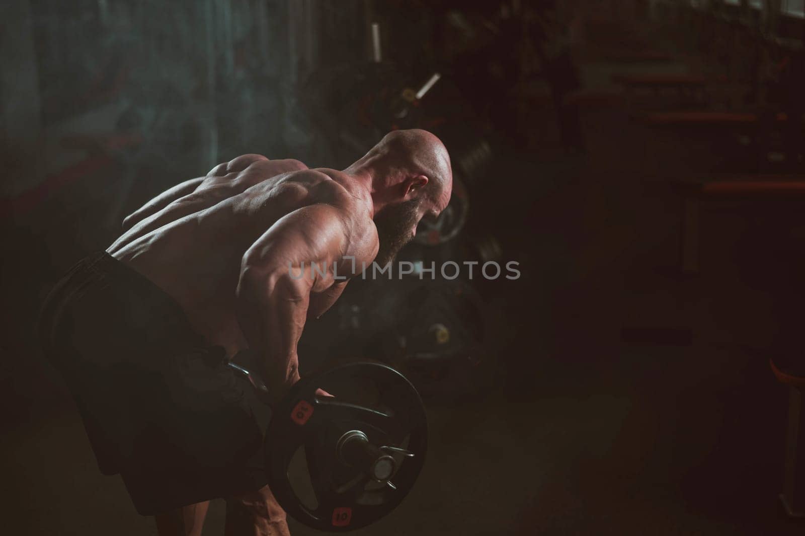 Caucasian bald topless man doing an exercise with a barbell in the gym